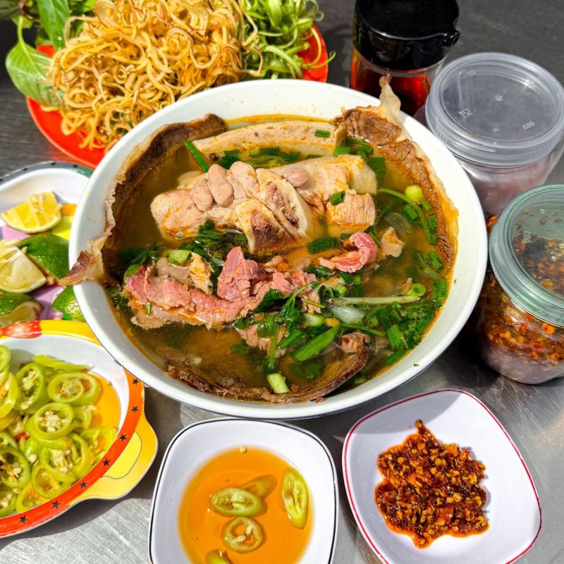 Tố bún nóng hổi, đầy ụ topping, rau đi kèm.