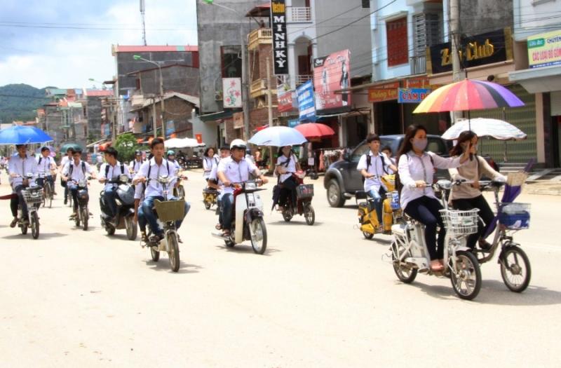 Học sinh dàn hàng ngang và sử dụng ô khi đi xe