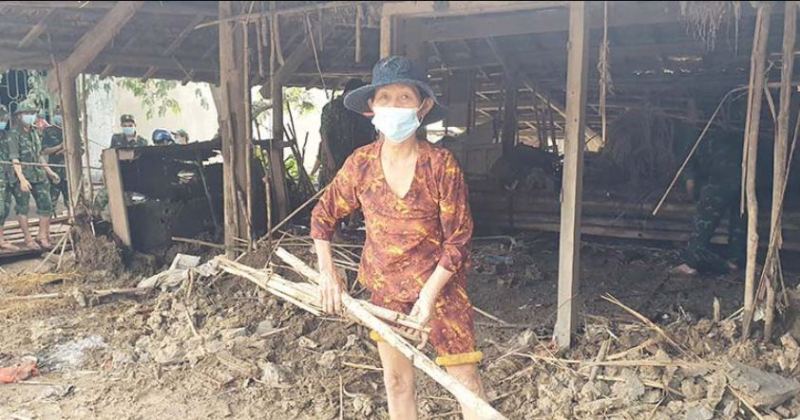Bà Phạm Thị Quờn nhặt nhạnh dưới căn nhà đổ nát sau lũ. (Ảnh: PLO)